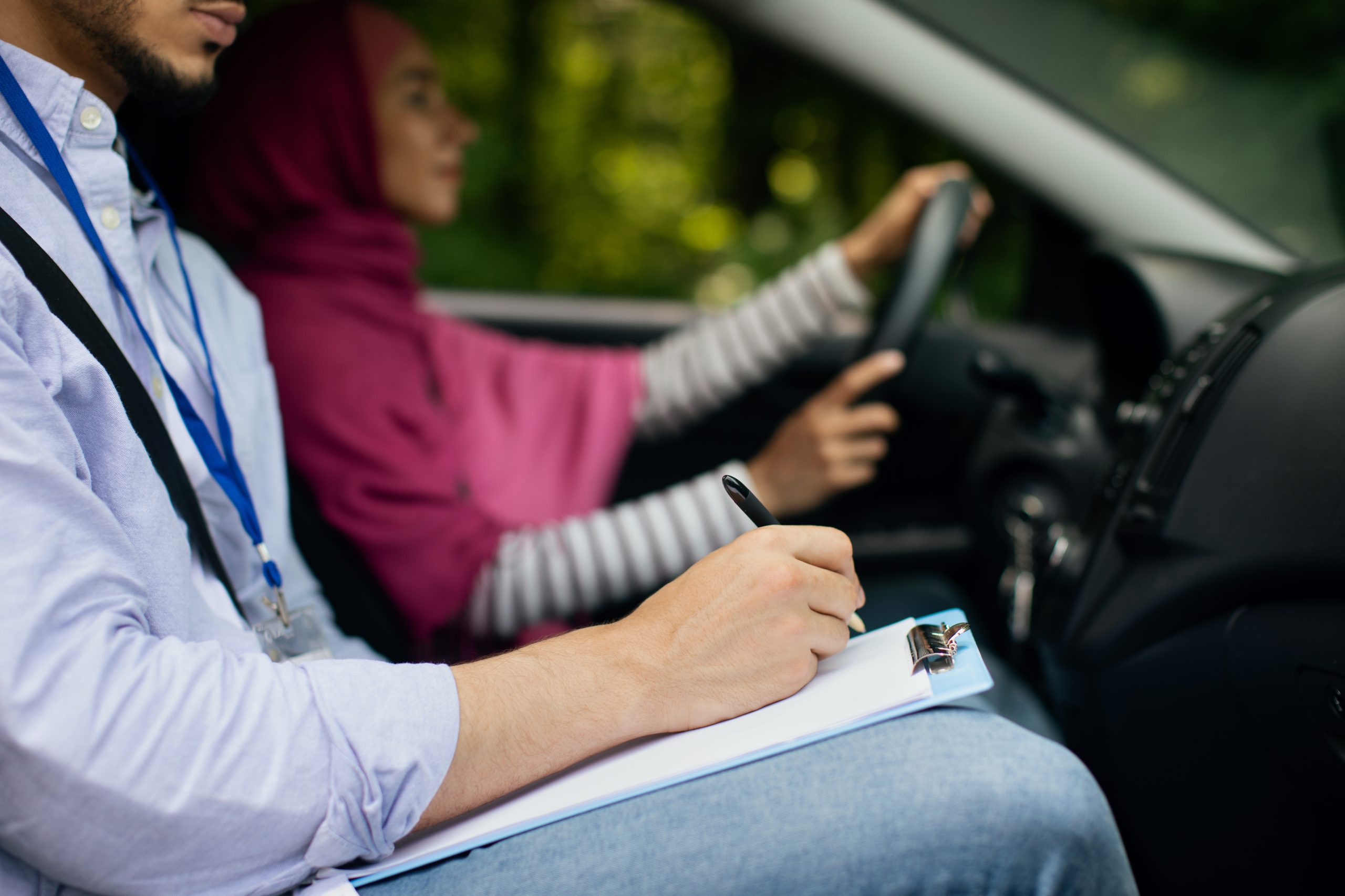 Driving School Concept. Male instructor examining muslim lady driver