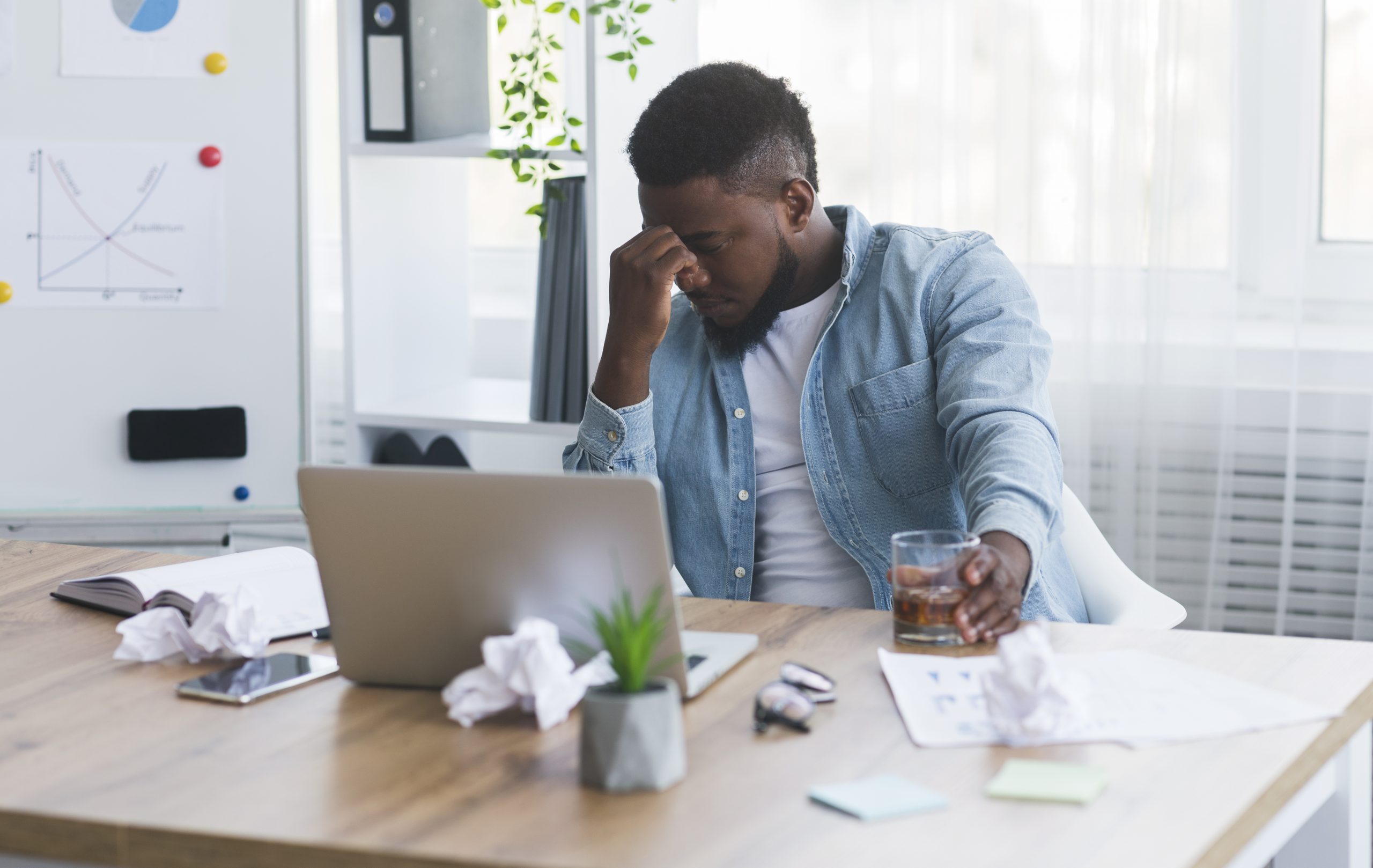 Stressed african american employee drinking alcohol at workplace